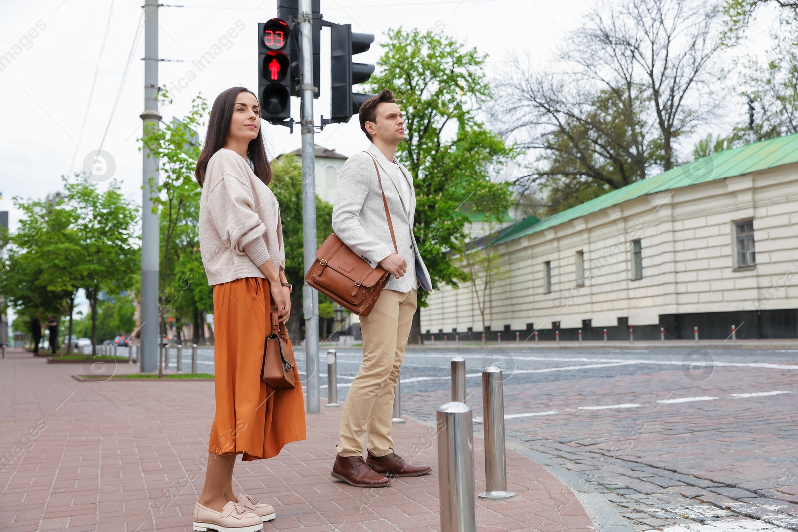 Young people waiting at traffic lights to cross street Photo of Young people waiting at traffic lights to cross street