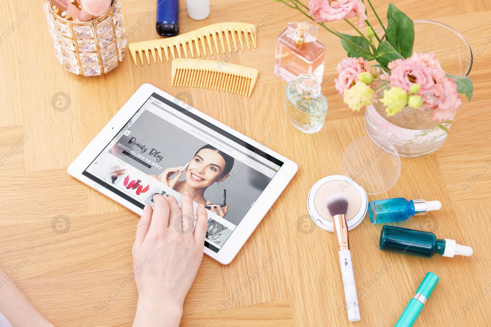 Blogger using tablet with beauty blog web site at wooden table indoors, above view Photo of Blogger using tablet with beauty blog web site at wooden table indoors, above view