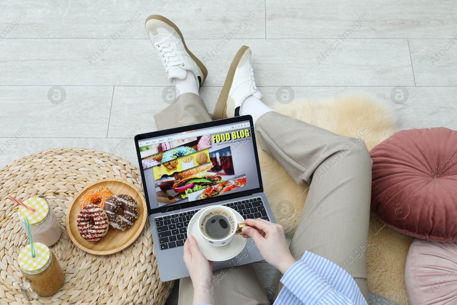Blogger holding coffee near laptop with food blog web site on floor indoors, above view Photo of Blogger holding coffee near laptop with food blog web site on floor indoors, above view