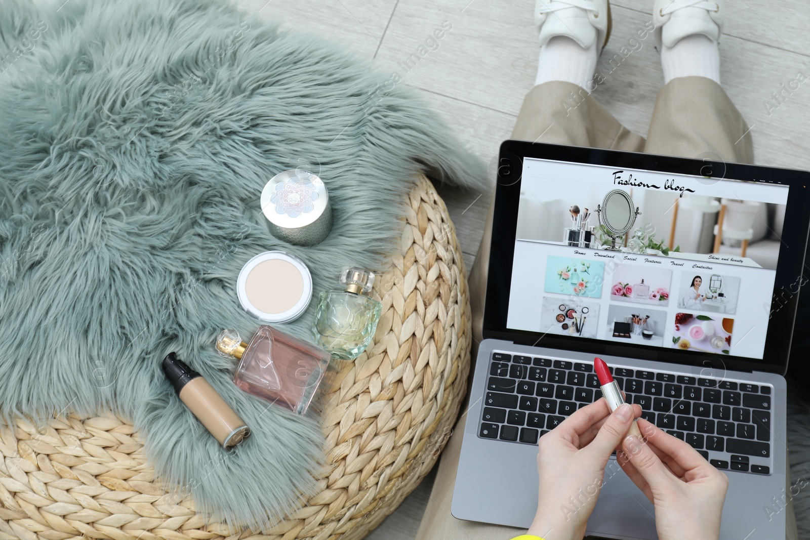 Blogger holding lipstick near laptop with fashion blog web site on floor indoors, above view Photo of Blogger holding lipstick near laptop with fashion blog web site on floor indoors, above view