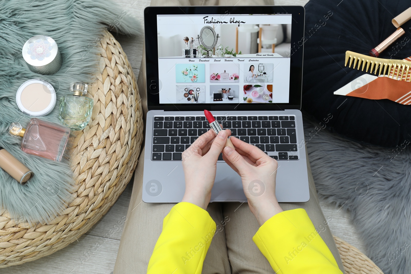 Blogger holding lipstick near laptop with fashion blog web site on floor indoors, above view Photo of Blogger holding lipstick near laptop with fashion blog web site on floor indoors, above view
