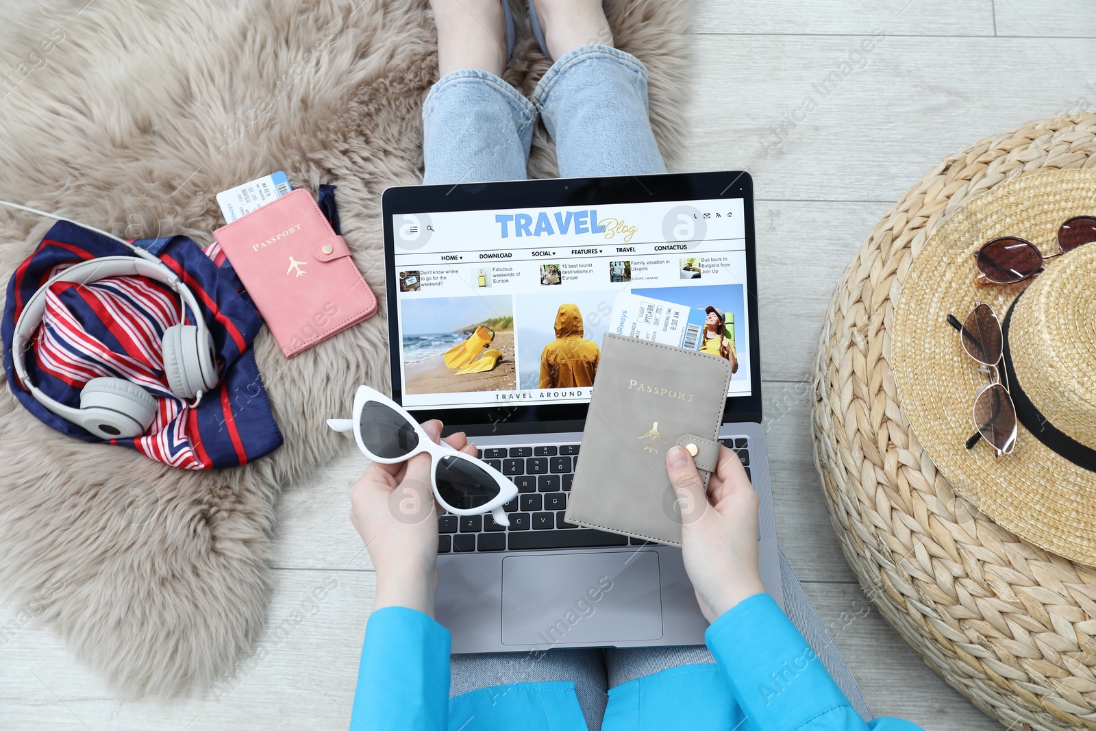 Blogger holding sunglasses, passport and flight ticket near laptop with travel blog web site on floor indoors, above view Photo of Blogger holding sunglasses, passport and flight ticket near laptop with travel blog web site on floor indoors, above view