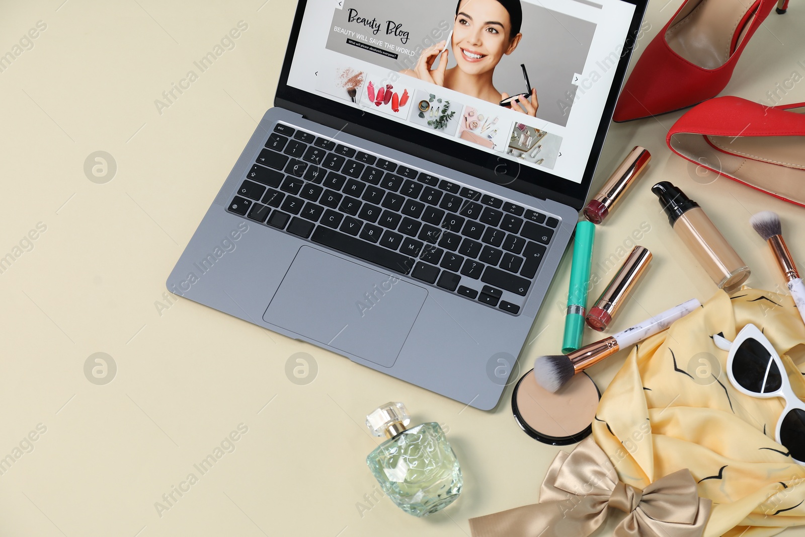 Laptop with beauty blog web site, shoes, accessories and makeup products on beige background, above view Photo of Laptop with beauty blog web site, shoes, accessories and makeup products on beige background, above view
