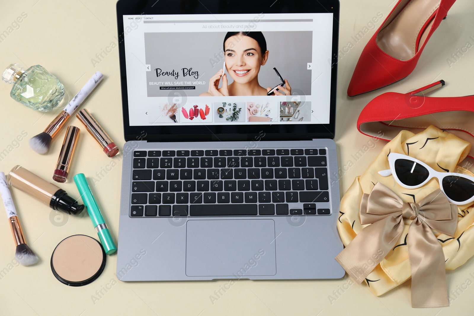 Laptop with beauty blog web site, shoes, accessories and makeup products on beige background, above view Photo of Laptop with beauty blog web site, shoes, accessories and makeup products on beige background, above view