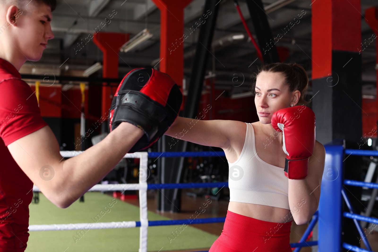 Woman in protective gloves having boxing practice with her coach at training center Photo of Woman in protective gloves having boxing practice with her coach at training center
