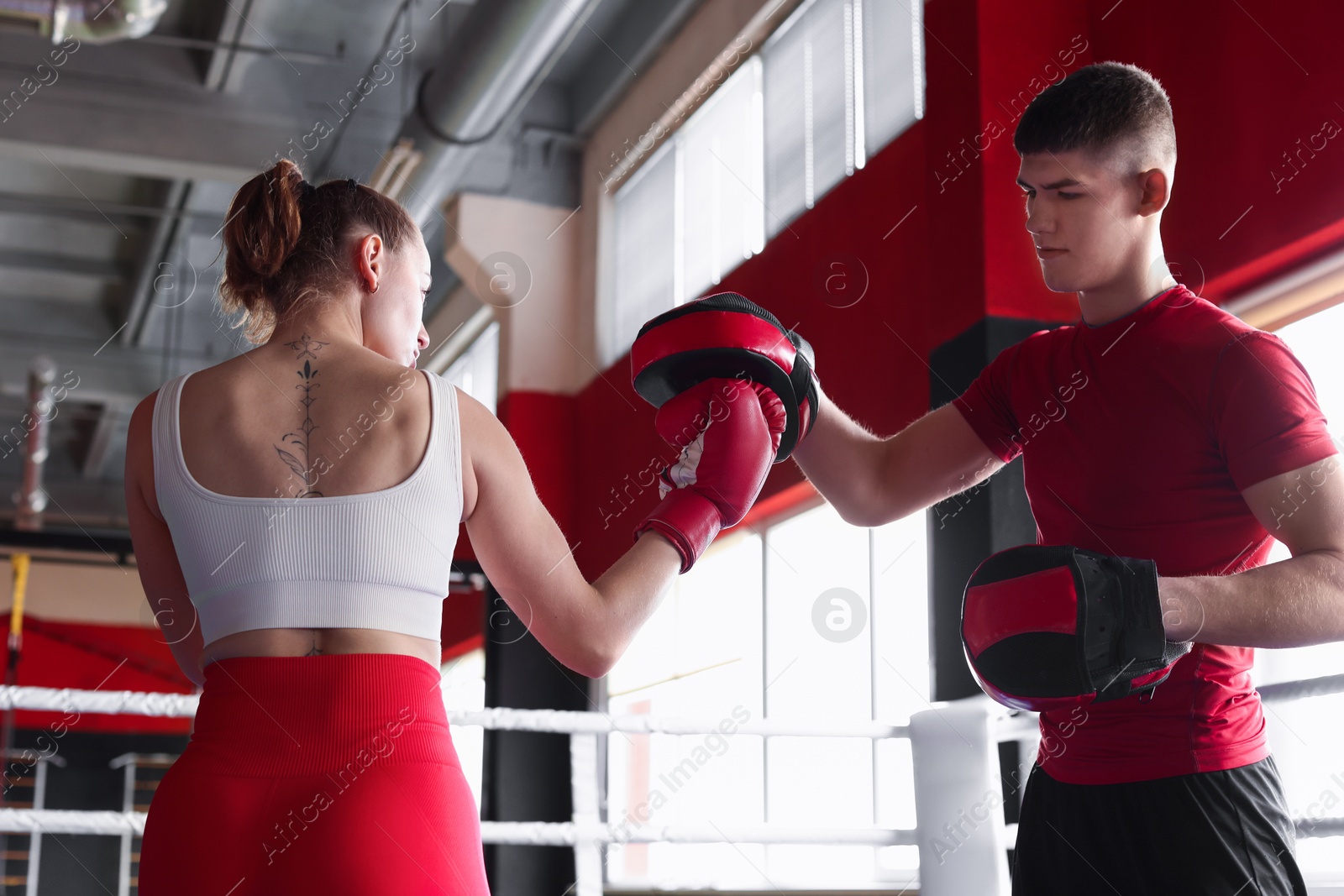 Woman in protective gloves having boxing practice with her coach at training center Photo of Woman in protective gloves having boxing practice with her coach at training center