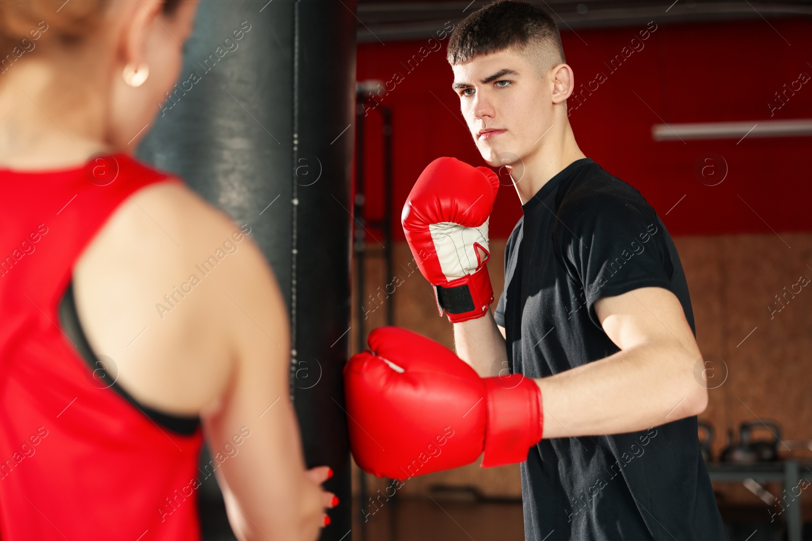 Boxing. Man and his coach practicing with punching bag in training center Photo of Boxing. Man and his coach practicing with punching bag in training center