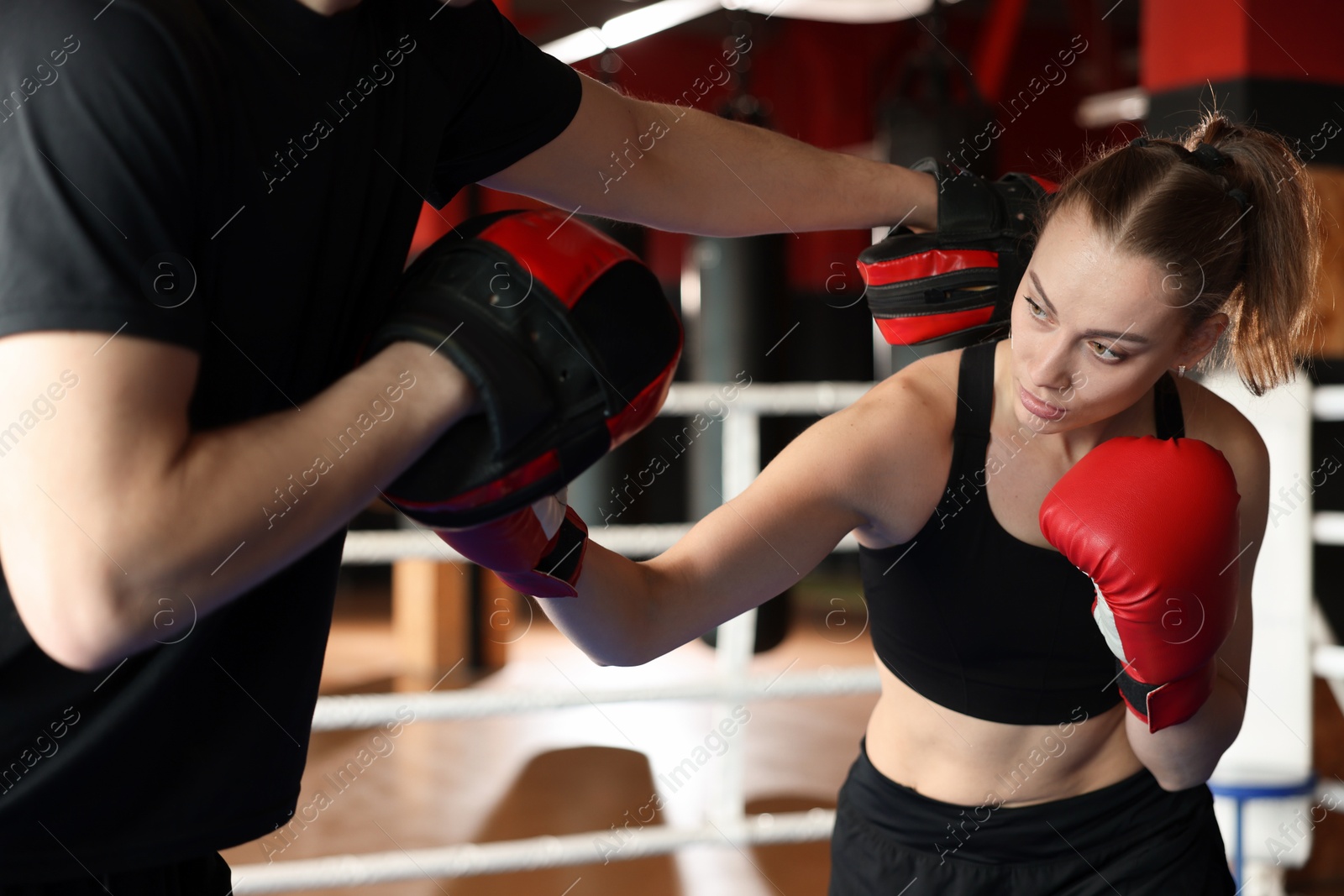 Woman in protective gloves having boxing practice with her coach at training center Photo of Woman in protective gloves having boxing practice with her coach at training center