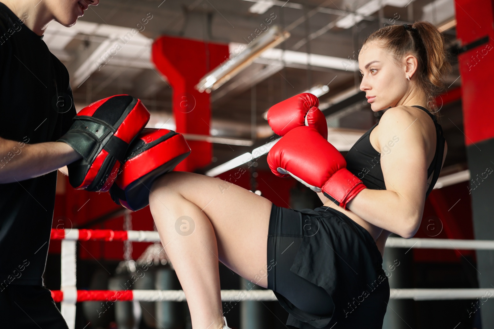 Woman in protective gloves having boxing practice with her coach at training center Photo of Woman in protective gloves having boxing practice with her coach at training center