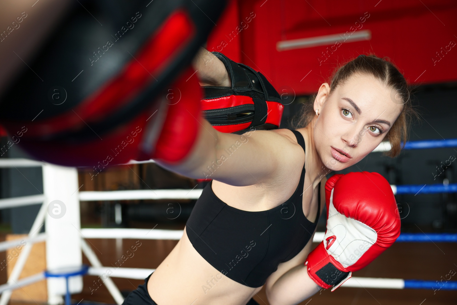 Woman in protective gloves having boxing practice with her coach at training center Photo of Woman in protective gloves having boxing practice with her coach at training center
