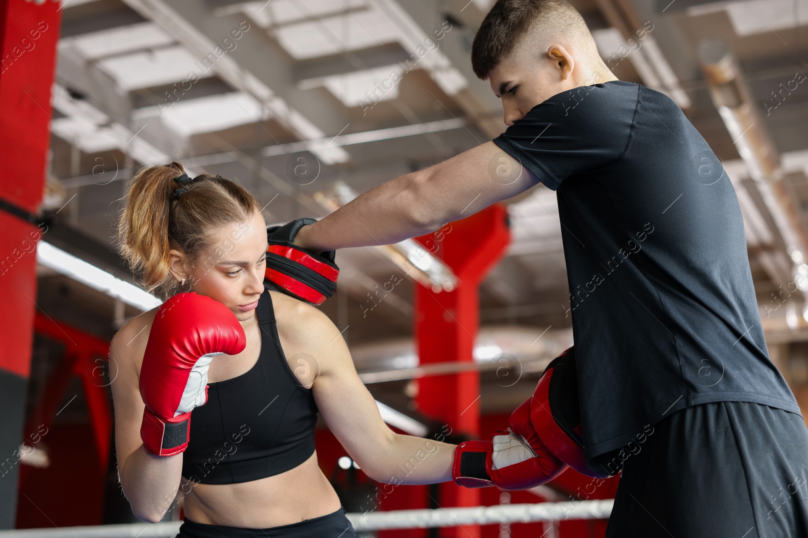 Woman in protective gloves having boxing practice with her coach at training center Photo of Woman in protective gloves having boxing practice with her coach at training center