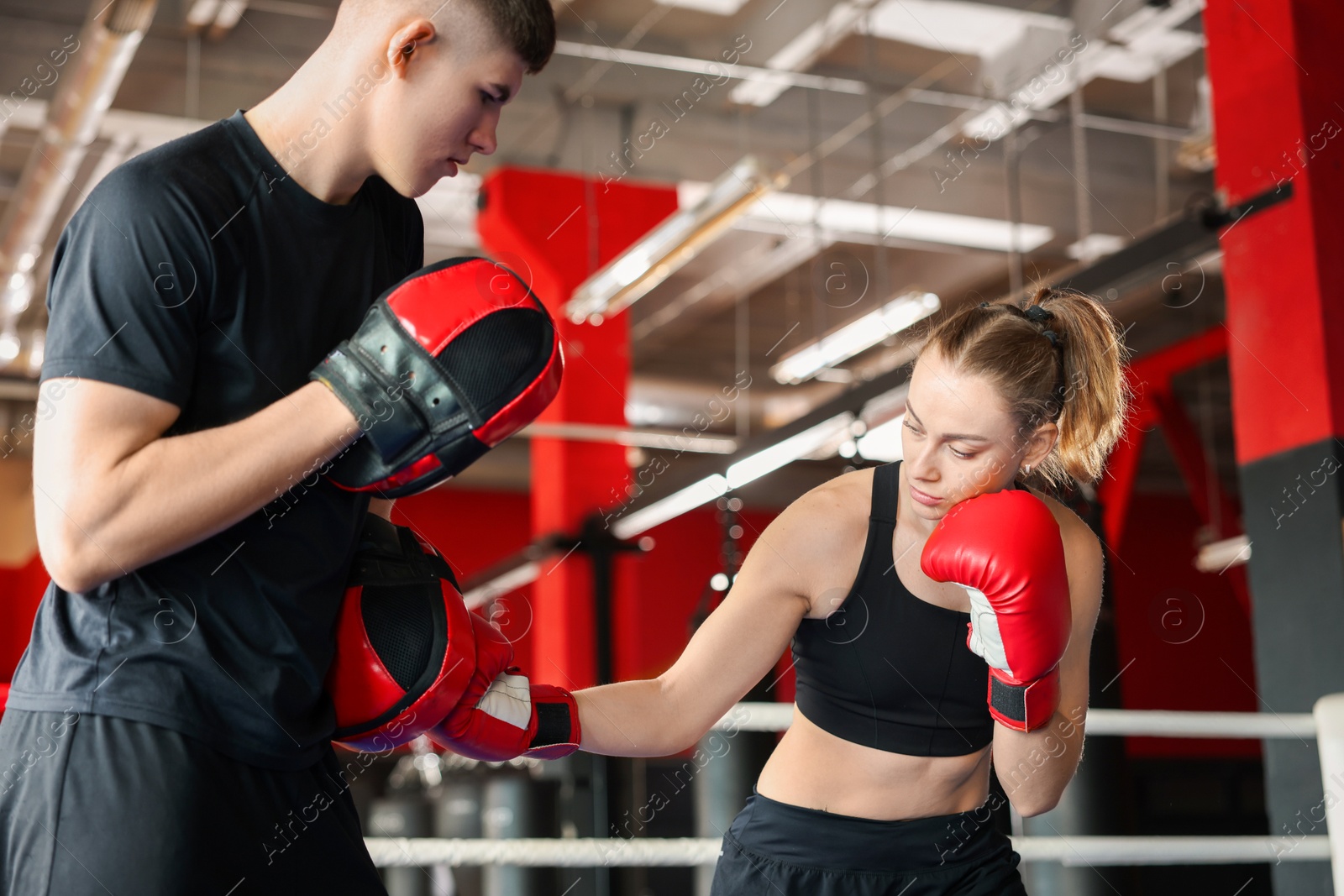 Woman in protective gloves having boxing practice with her coach at training center Photo of Woman in protective gloves having boxing practice with her coach at training center