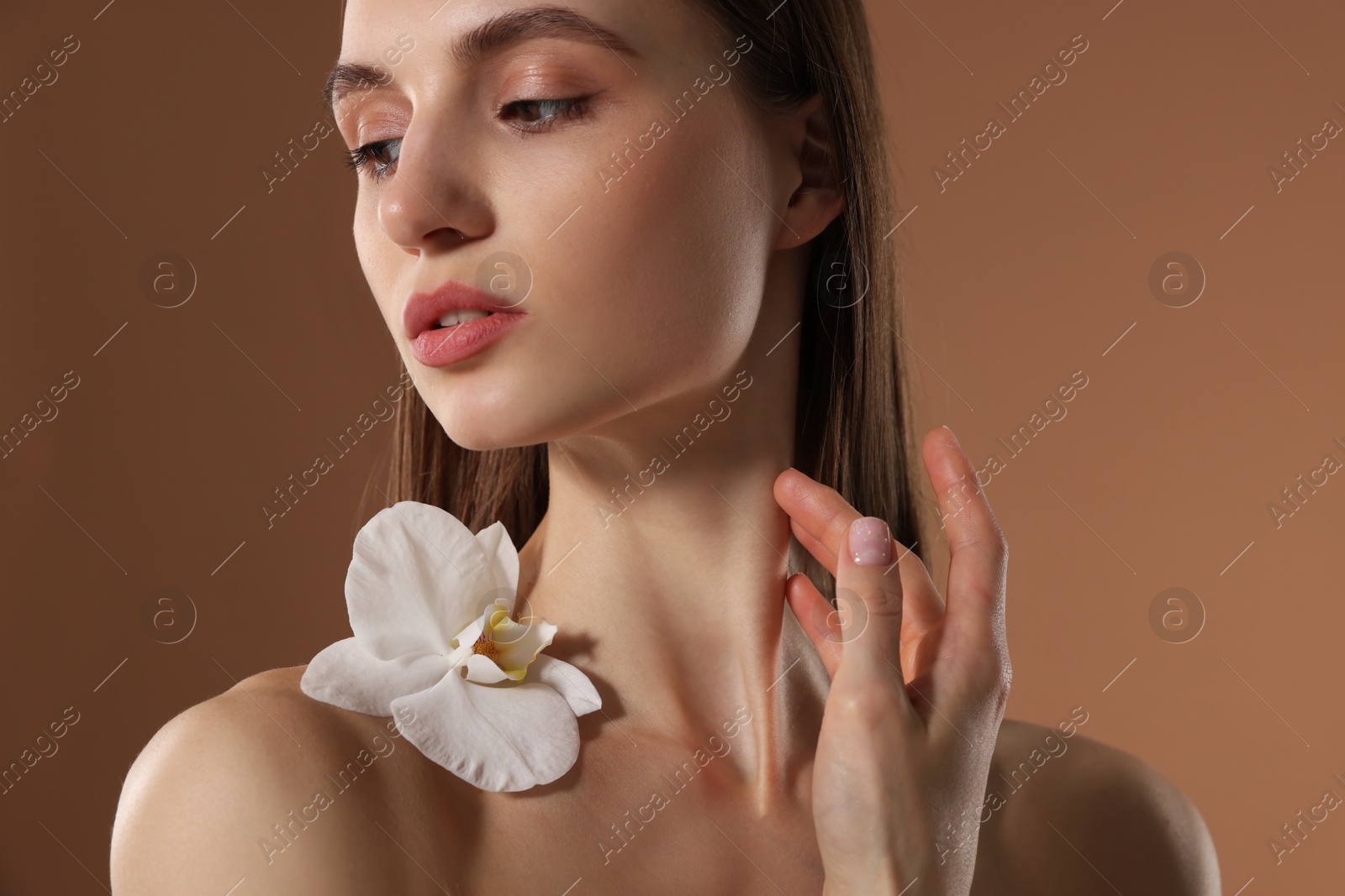 Beautiful woman with orchid flower on beige background Photo of Beautiful woman with orchid flower on beige background