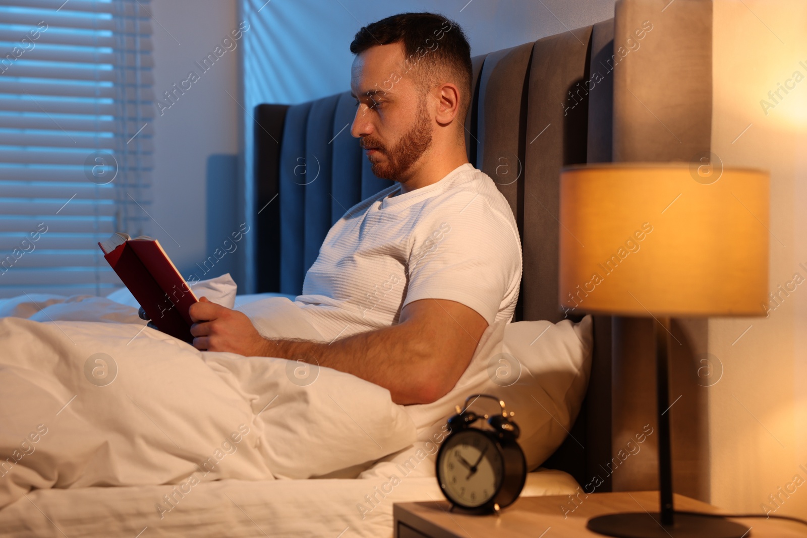 Young man reading book in bed at home Photo of Young man reading book in bed at home