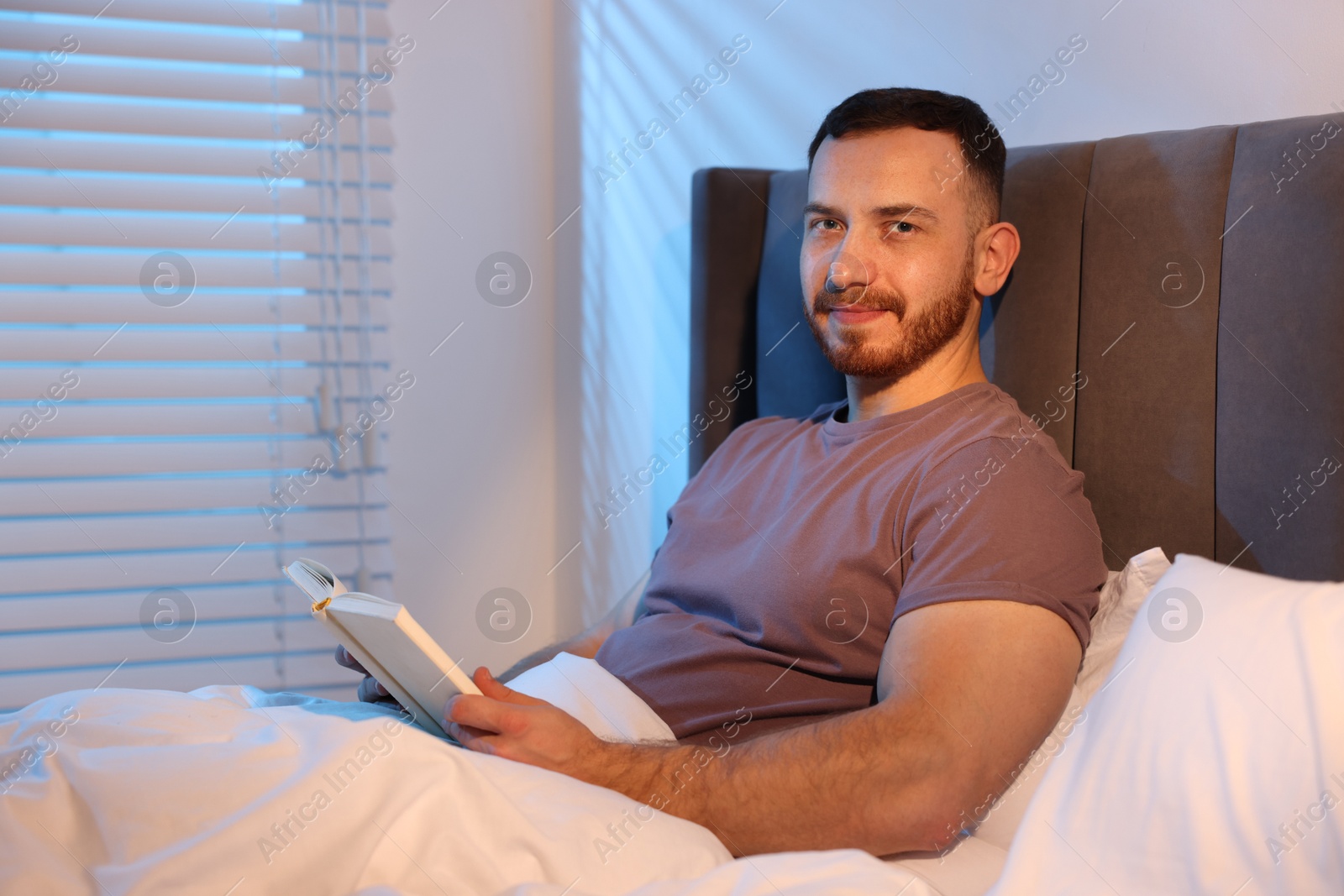 Young man with book in bed at home Photo of Young man with book in bed at home