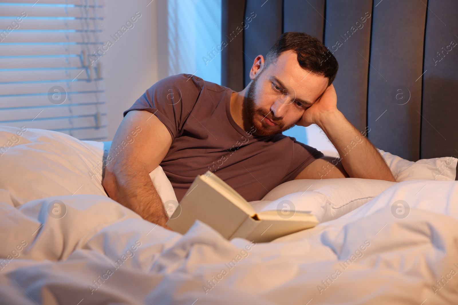 Young man reading book in bed at home Photo of Young man reading book in bed at home