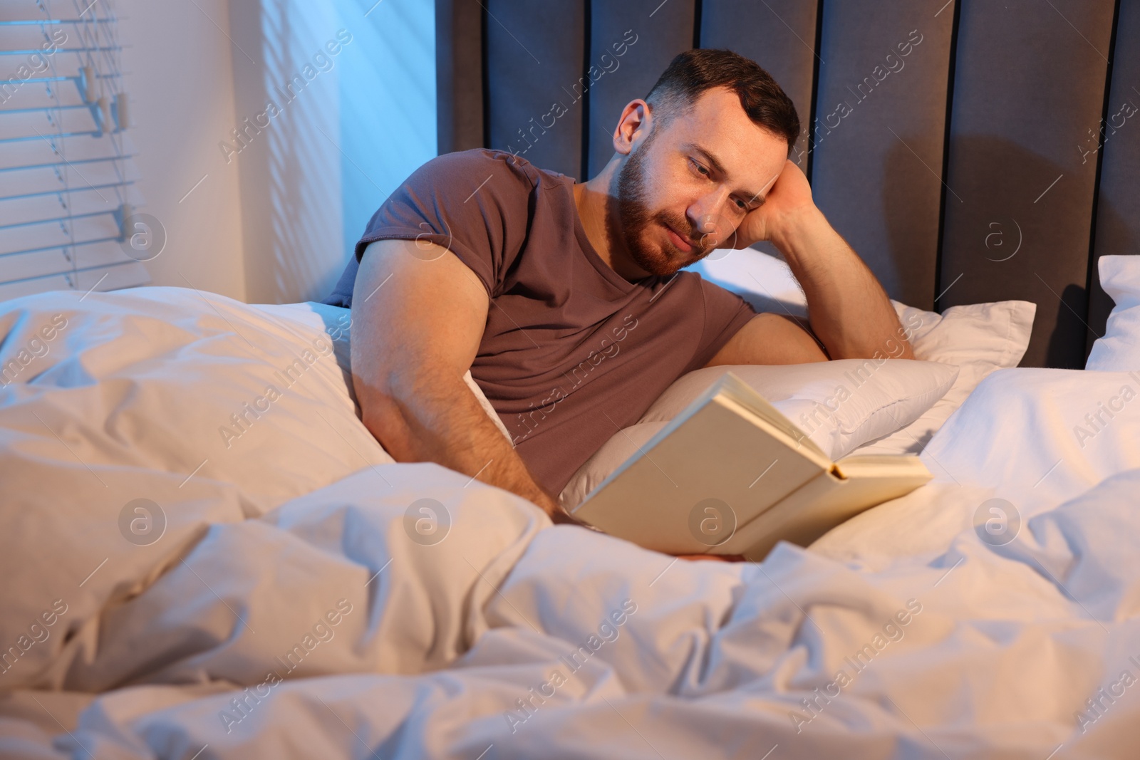 Young man reading book in bed at home Photo of Young man reading book in bed at home