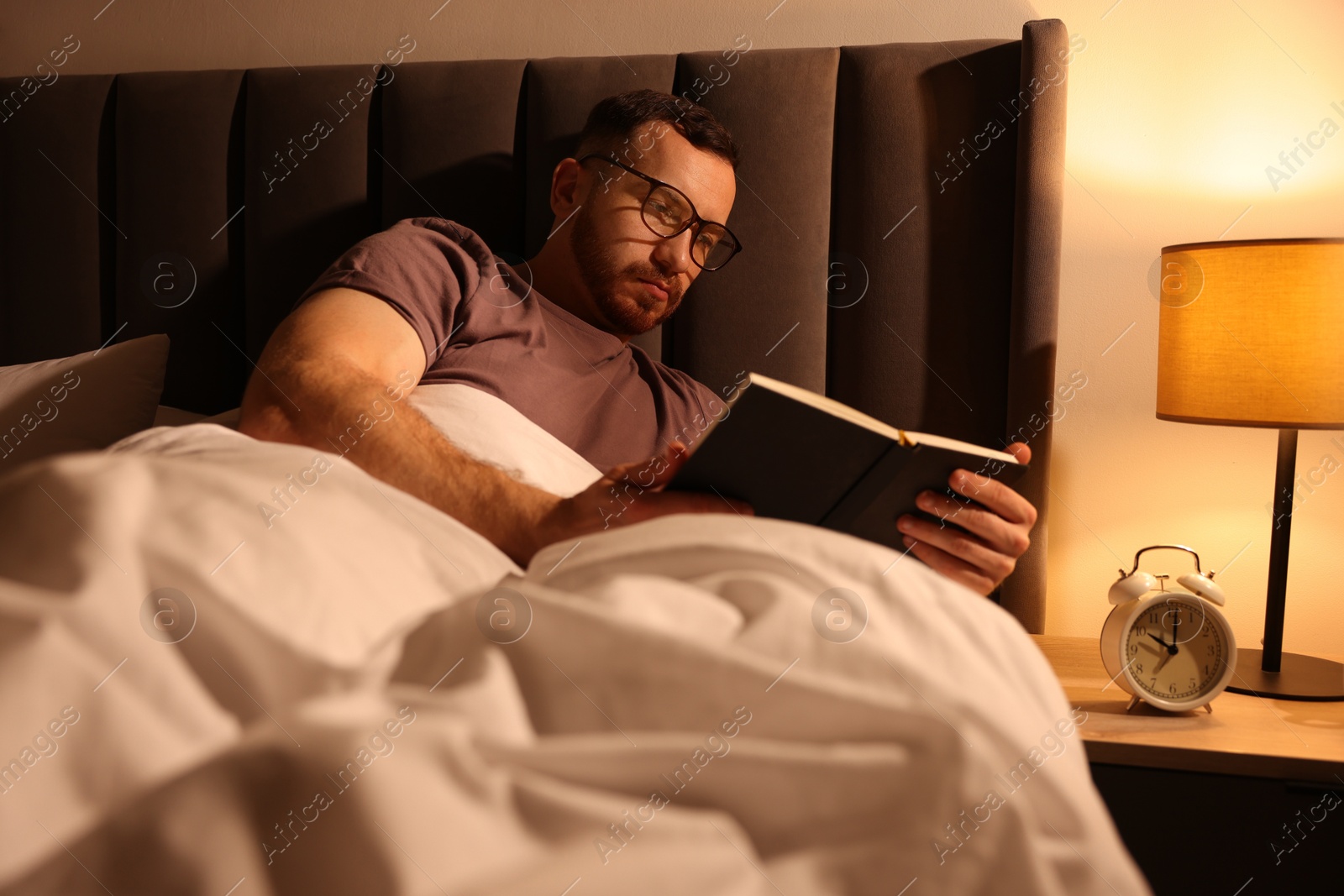 Young man reading book in bed at home Photo of Young man reading book in bed at home