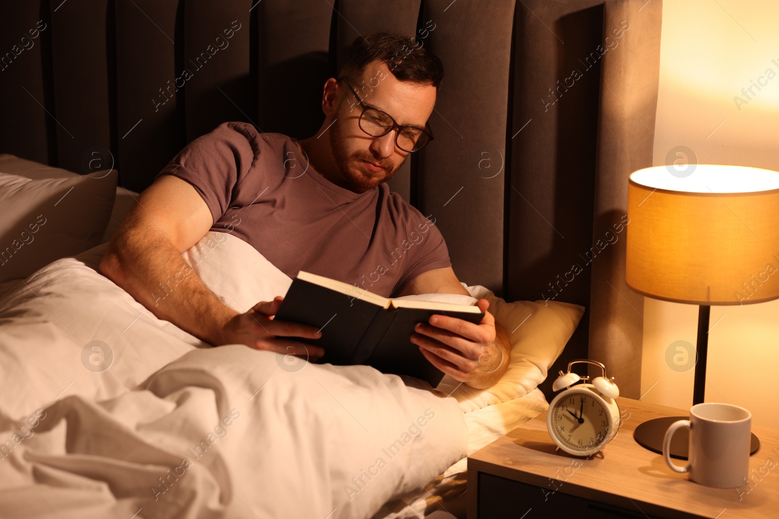 Young man reading book in bed at home Photo of Young man reading book in bed at home