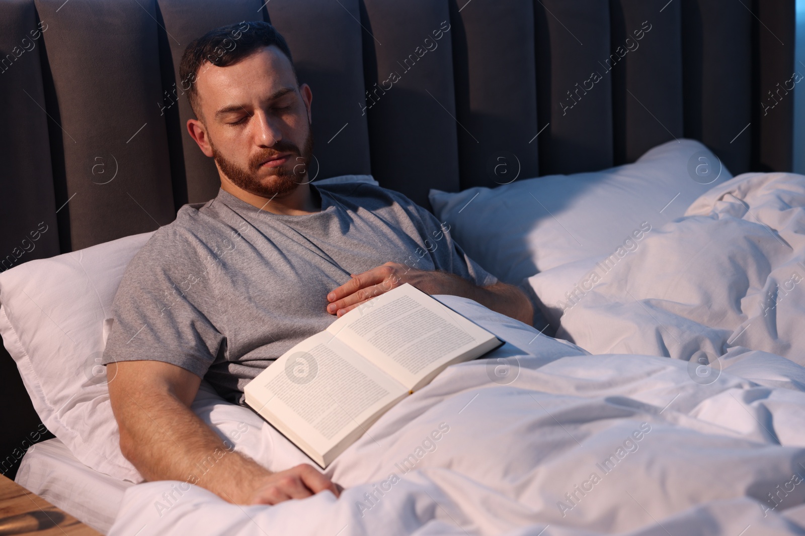 Young man sleeping with book in bed at home Photo of Young man sleeping with book in bed at home