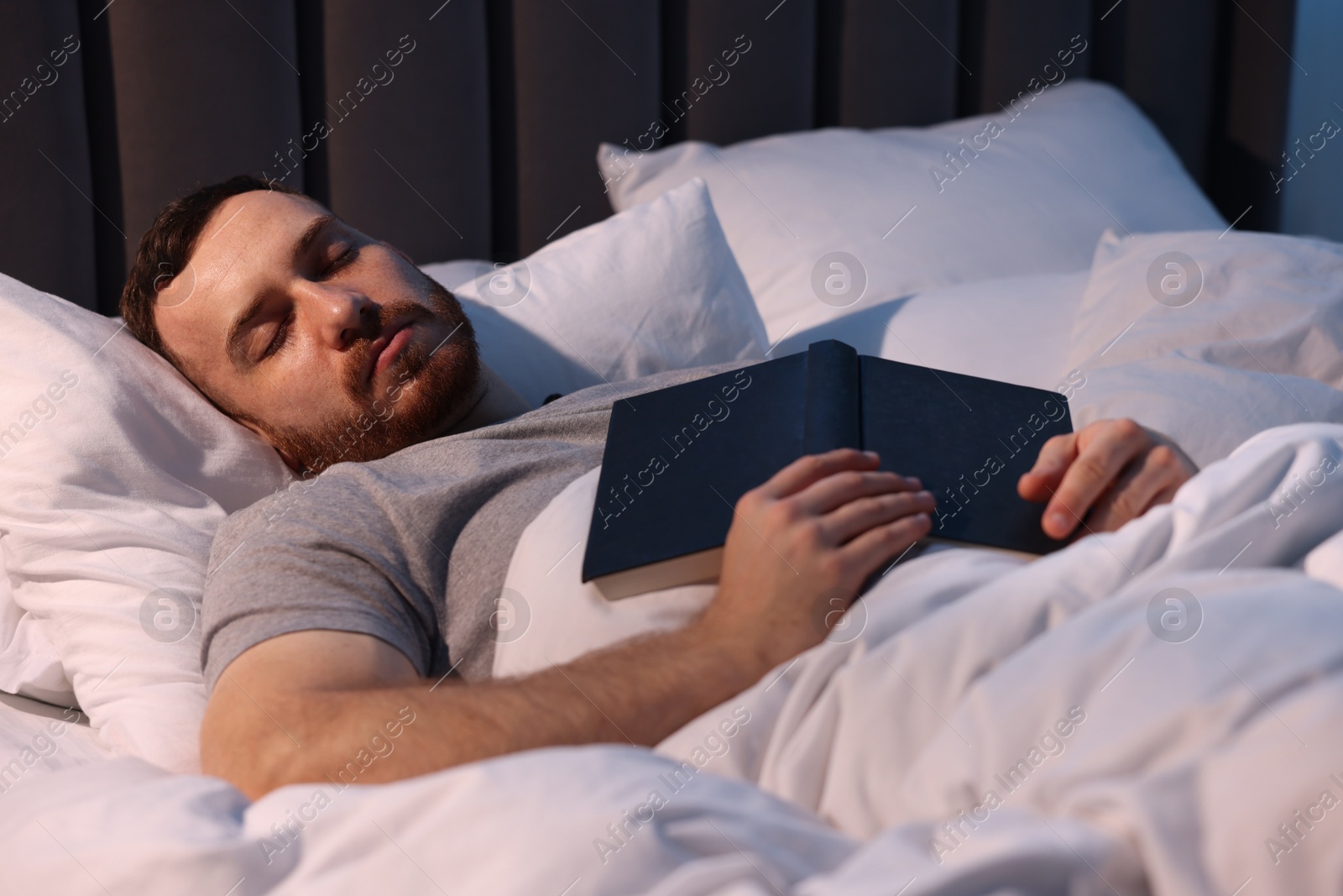 Young man sleeping with book in bed at home Photo of Young man sleeping with book in bed at home