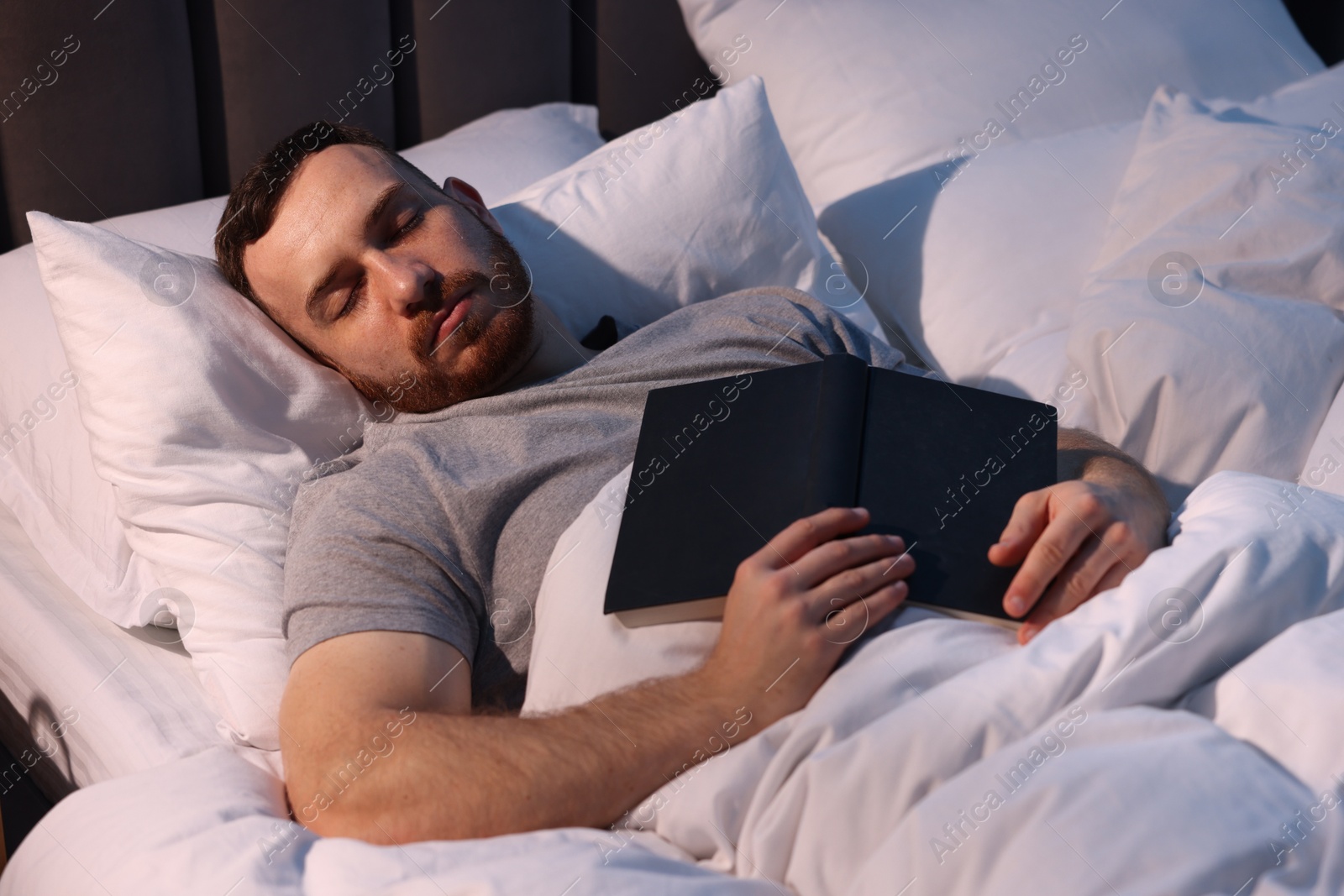 Young man sleeping with book in bed at home Photo of Young man sleeping with book in bed at home