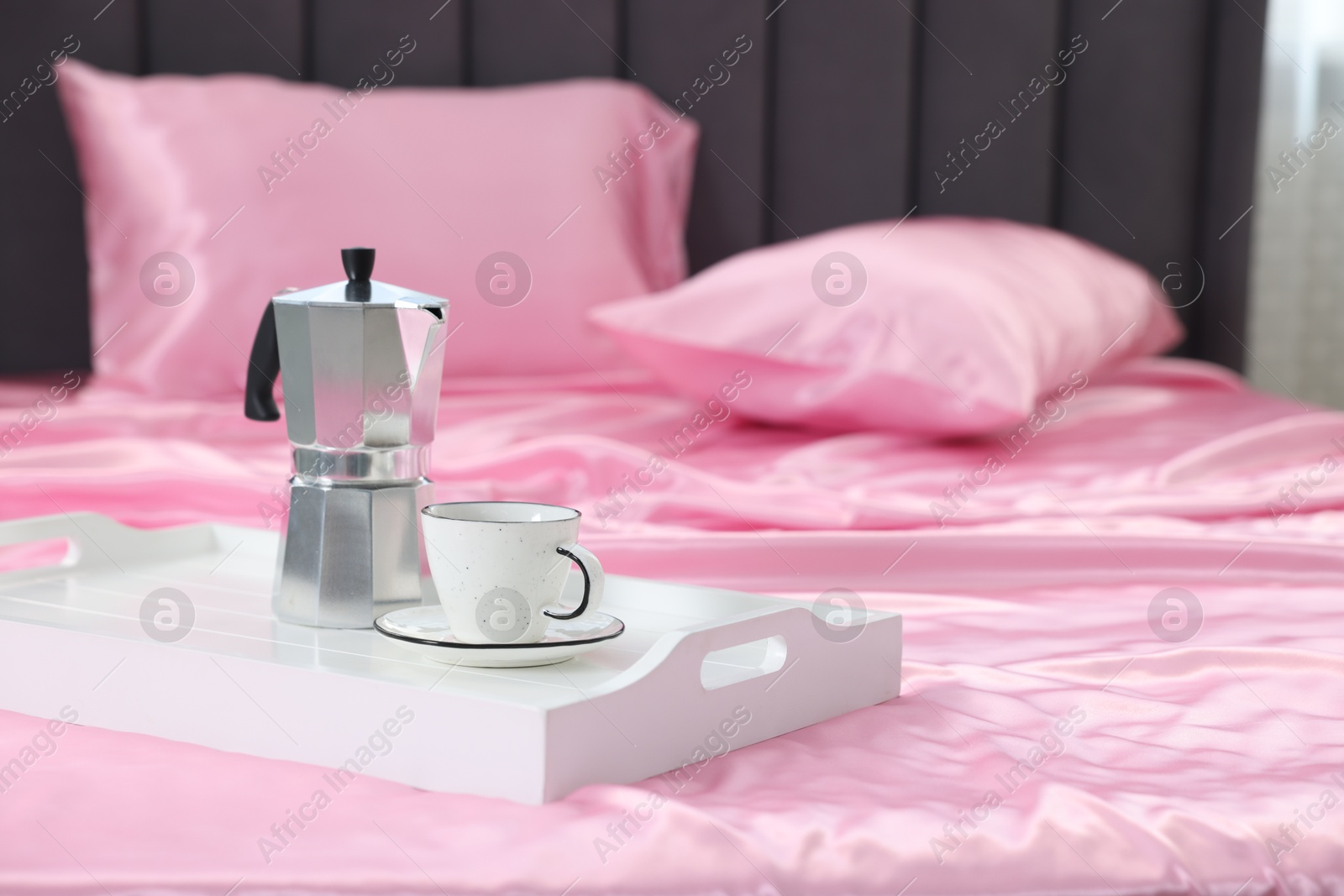 Moka pot and cup of coffee on bed with silk linens, closeup Photo of Moka pot and cup of coffee on bed with silk linens, closeup