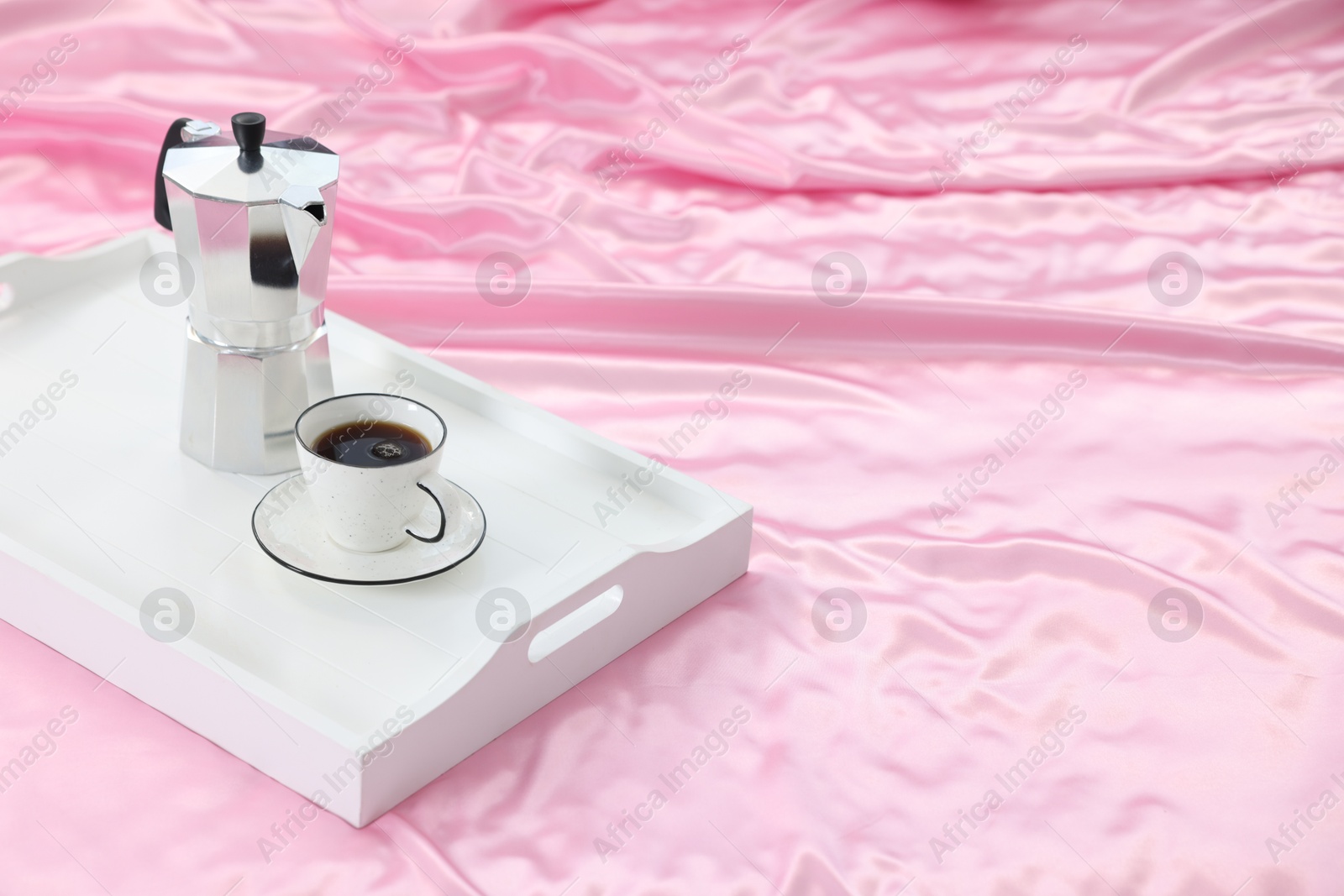 Moka pot and cup of coffee on bed with silk linens, closeup. Space for text Photo of Moka pot and cup of coffee on bed with silk linens, closeup. Space for text