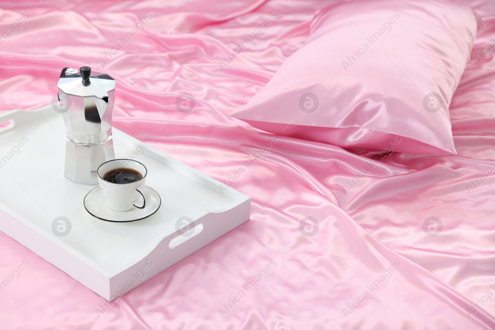 Moka pot and cup of coffee on bed with silk linens Photo of Moka pot and cup of coffee on bed with silk linens