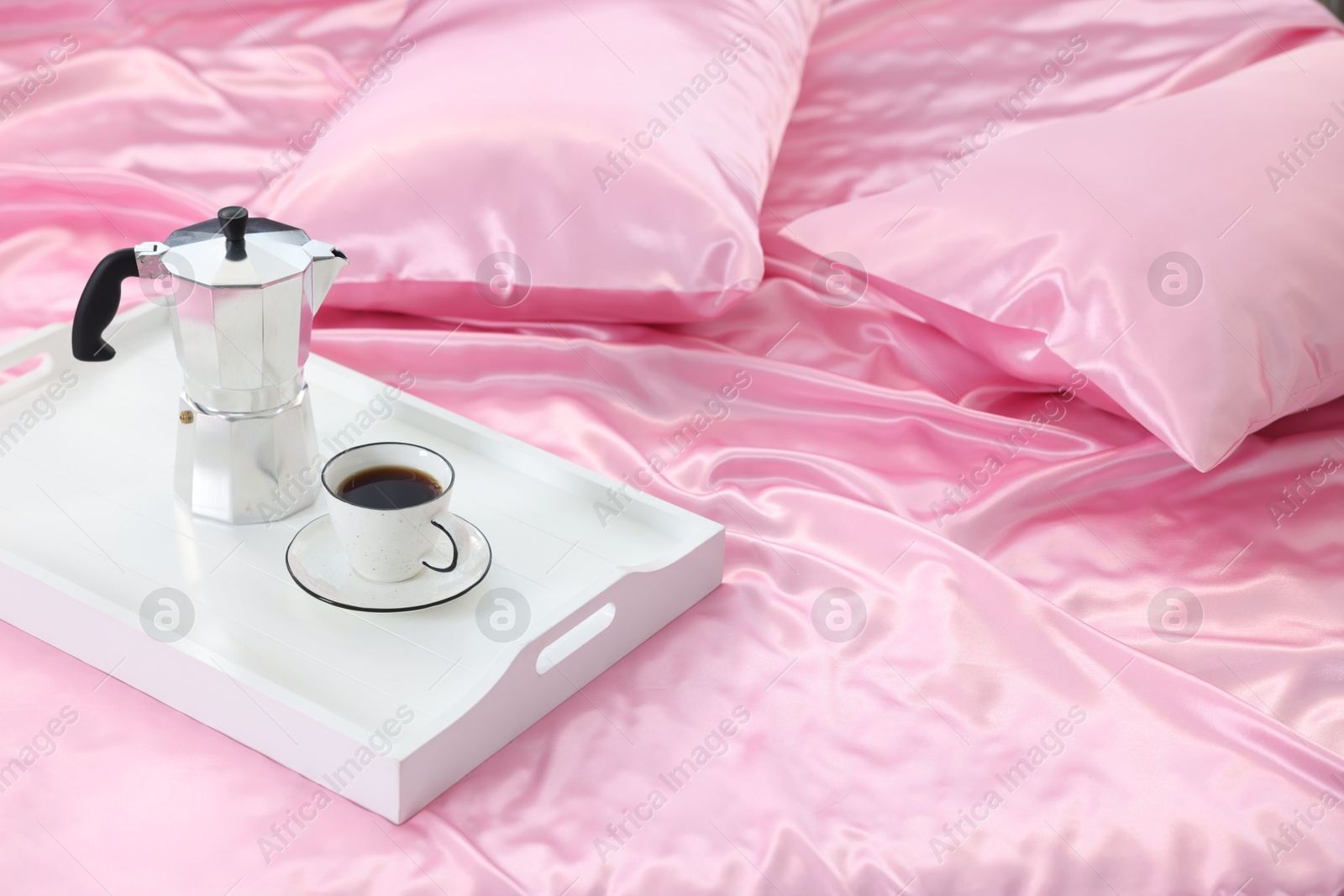 Moka pot and cup of coffee on bed with silk linens Photo of Moka pot and cup of coffee on bed with silk linens