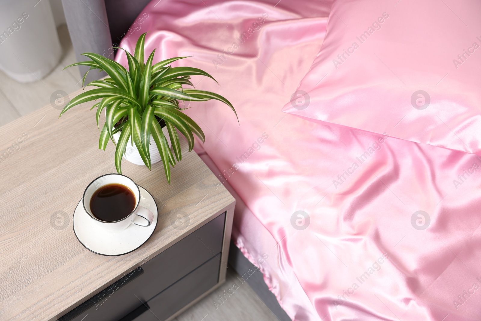 Luxury silk linens on bed and nightstand at home, above view Photo of Luxury silk linens on bed and nightstand at home, above view