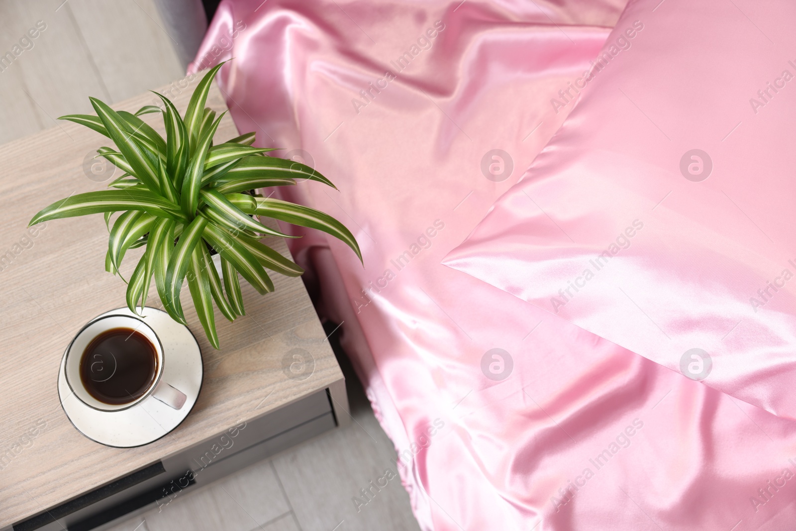 Luxury silk linens on bed and nightstand at home, above view Photo of Luxury silk linens on bed and nightstand at home, above view