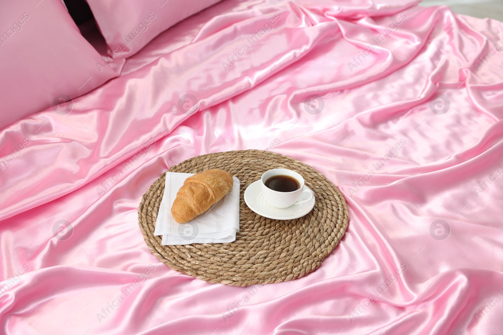 Mat with coffee and croissant on silk bed linens Photo of Mat with coffee and croissant on silk bed linens
