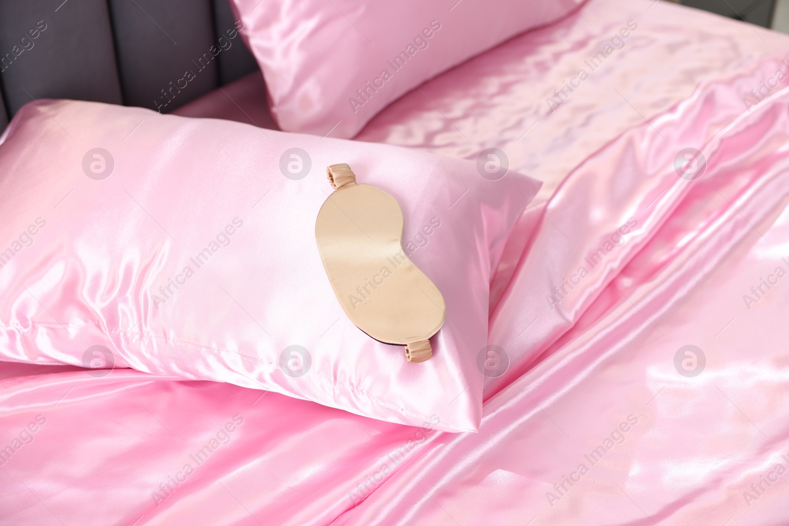 Luxury pink silk linens and sleep mask on bed Photo of Luxury pink silk linens and sleep mask on bed
