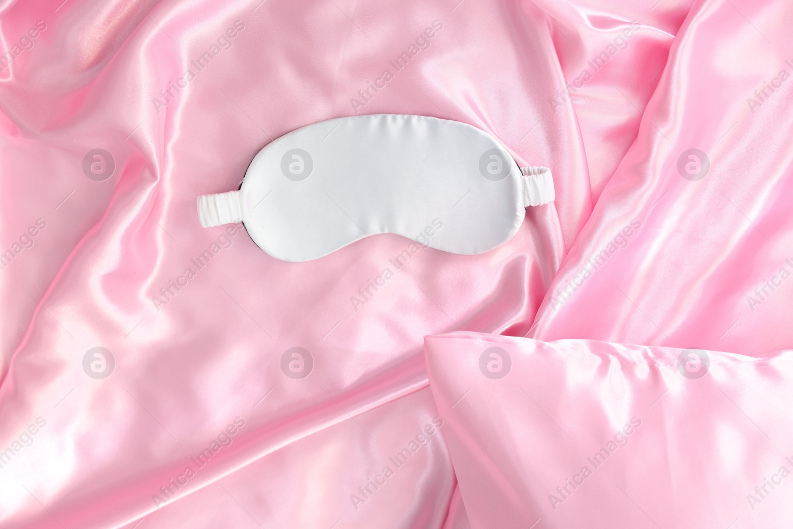 Luxury pink silk linens and sleep mask on bed, top view Photo of Luxury pink silk linens and sleep mask on bed, top view