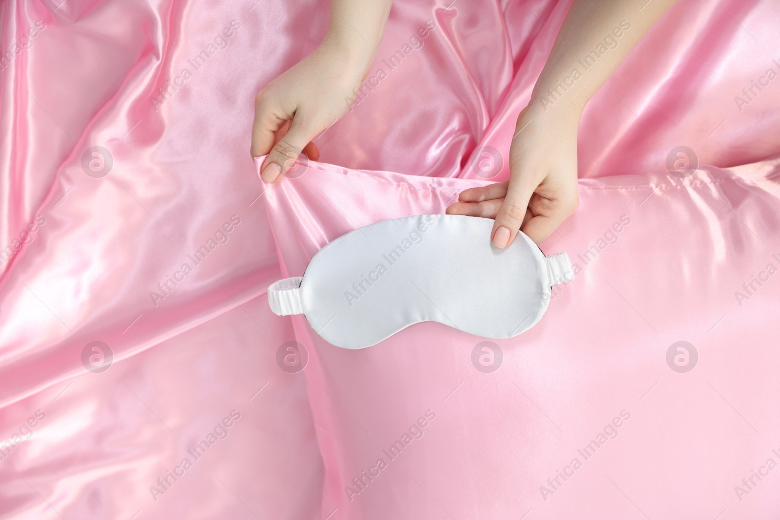 Woman with sleep mask on silk bed linens, top view Photo of Woman with sleep mask on silk bed linens, top view