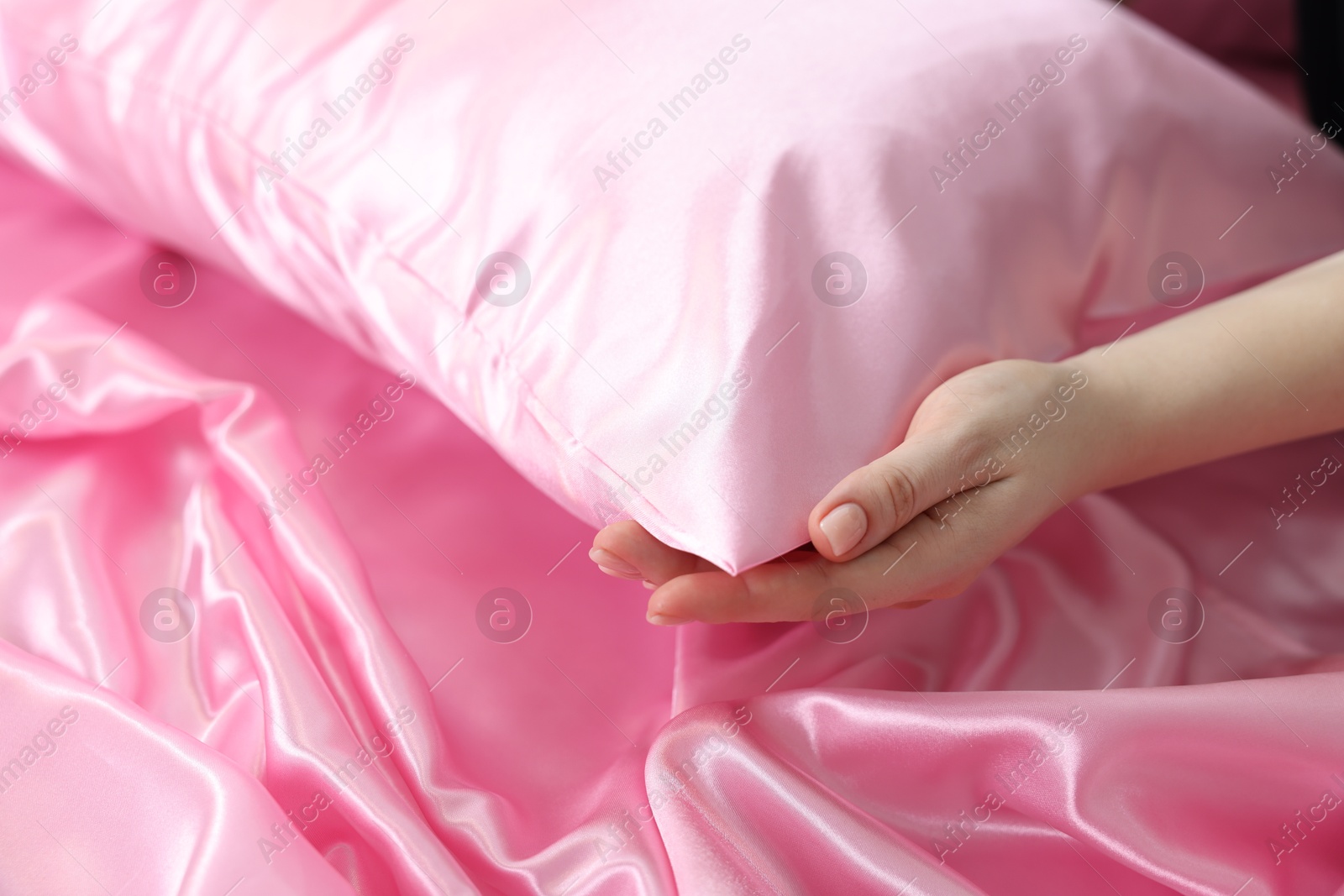 Woman with pillow and silk bed linens, closeup Photo of Woman with pillow and silk bed linens, closeup