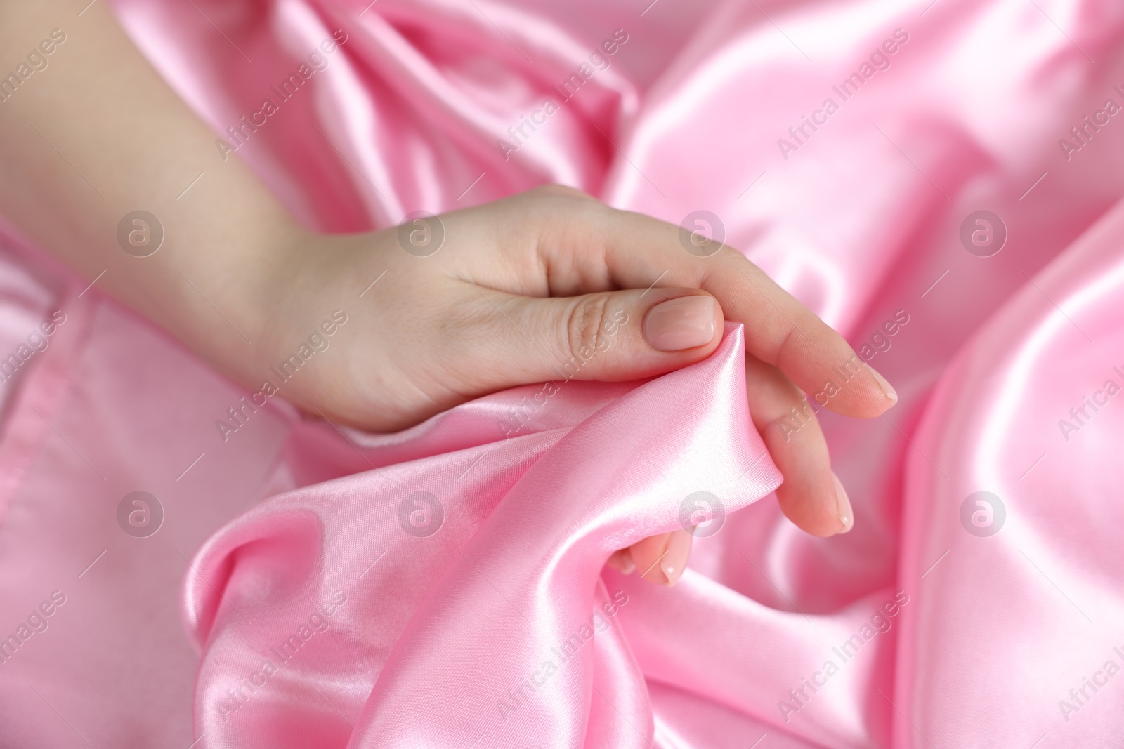 Woman with pink silk bed linens, closeup Photo of Woman with pink silk bed linens, closeup