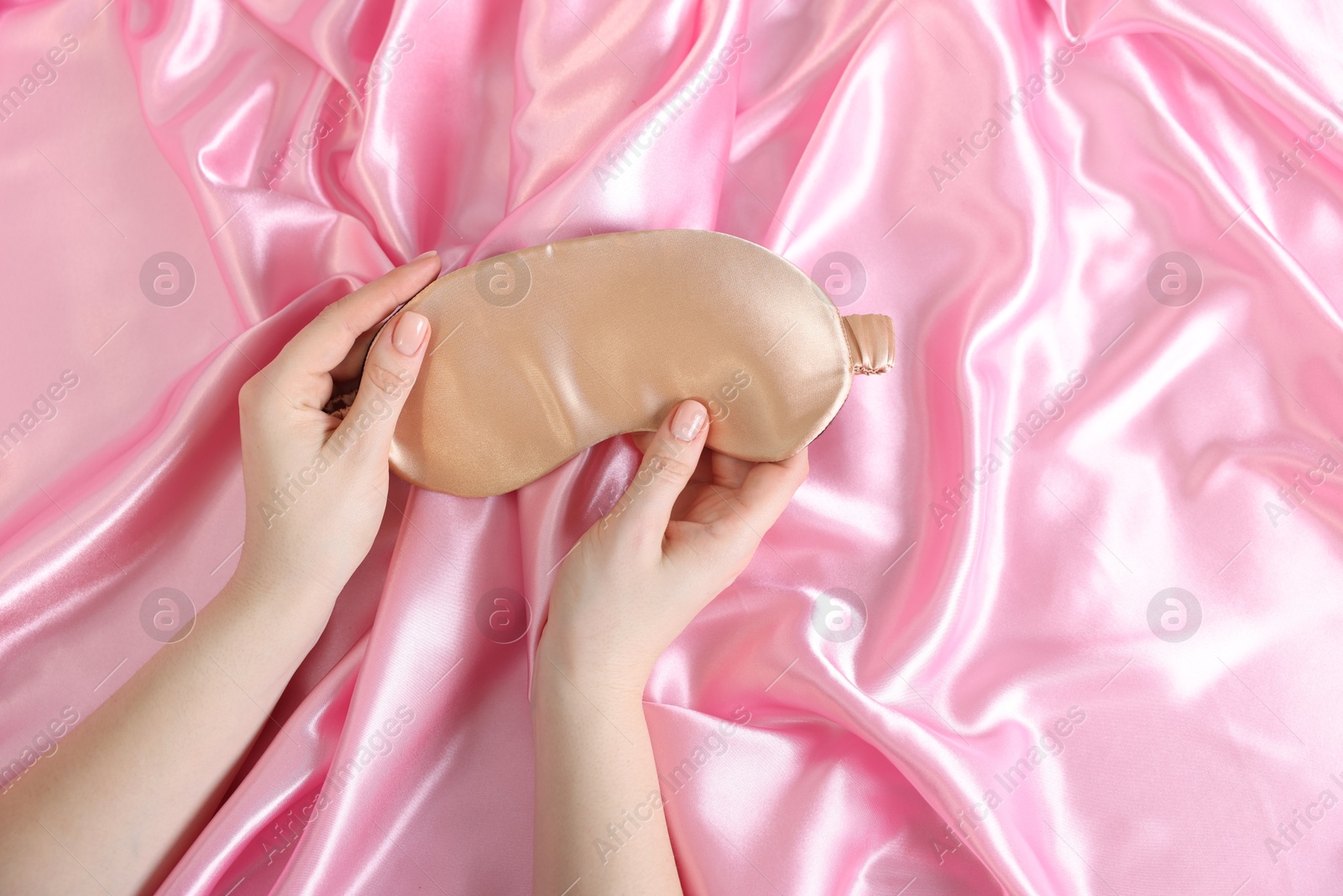Woman with sleep mask on silk bed linens, top view Photo of Woman with sleep mask on silk bed linens, top view