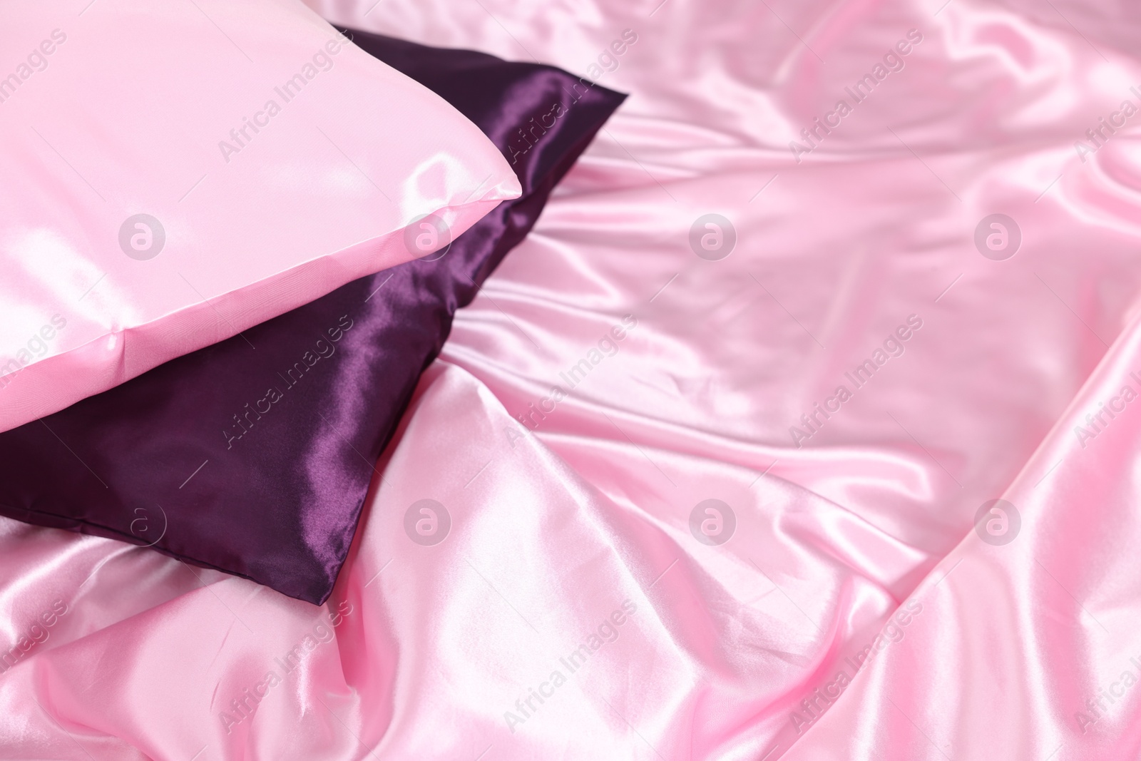 Luxury pink silk linens and pillows on bed, closeup Photo of Luxury pink silk linens and pillows on bed, closeup