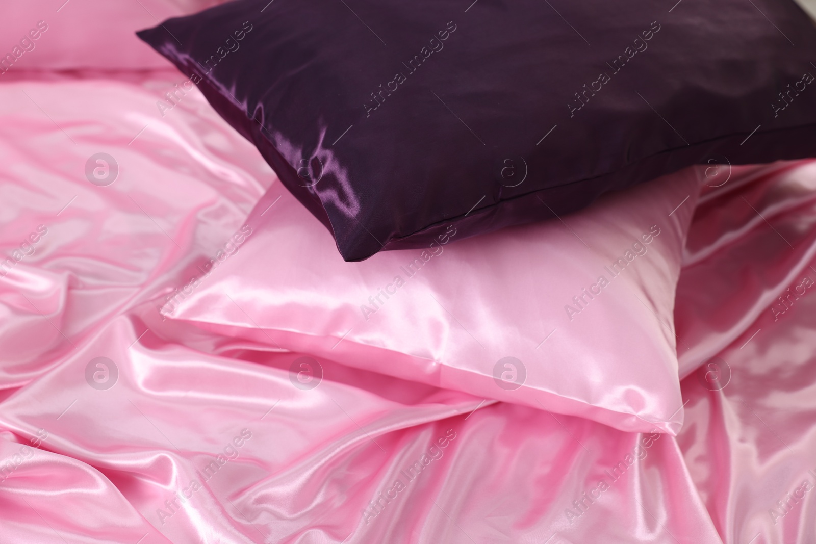Luxury pink silk linens and pillows on bed, closeup Photo of Luxury pink silk linens and pillows on bed, closeup