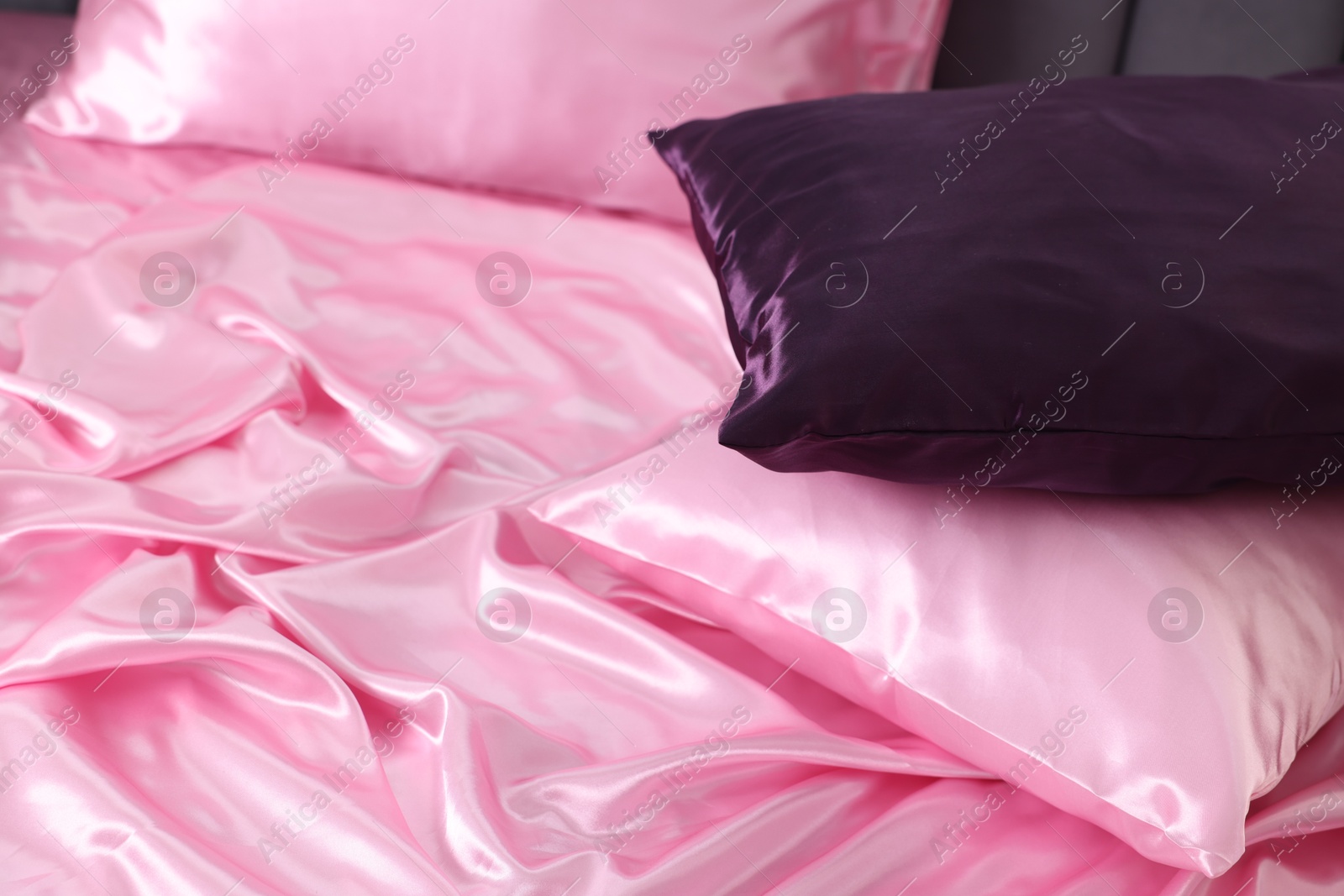 Luxury pink silk linens and pillows on bed, closeup Photo of Luxury pink silk linens and pillows on bed, closeup
