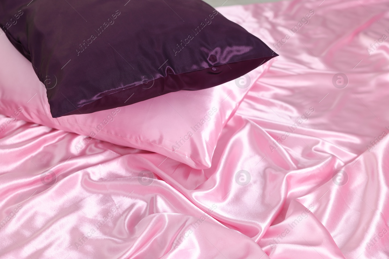 Luxury pink silk linens and pillows on bed, closeup Photo of Luxury pink silk linens and pillows on bed, closeup