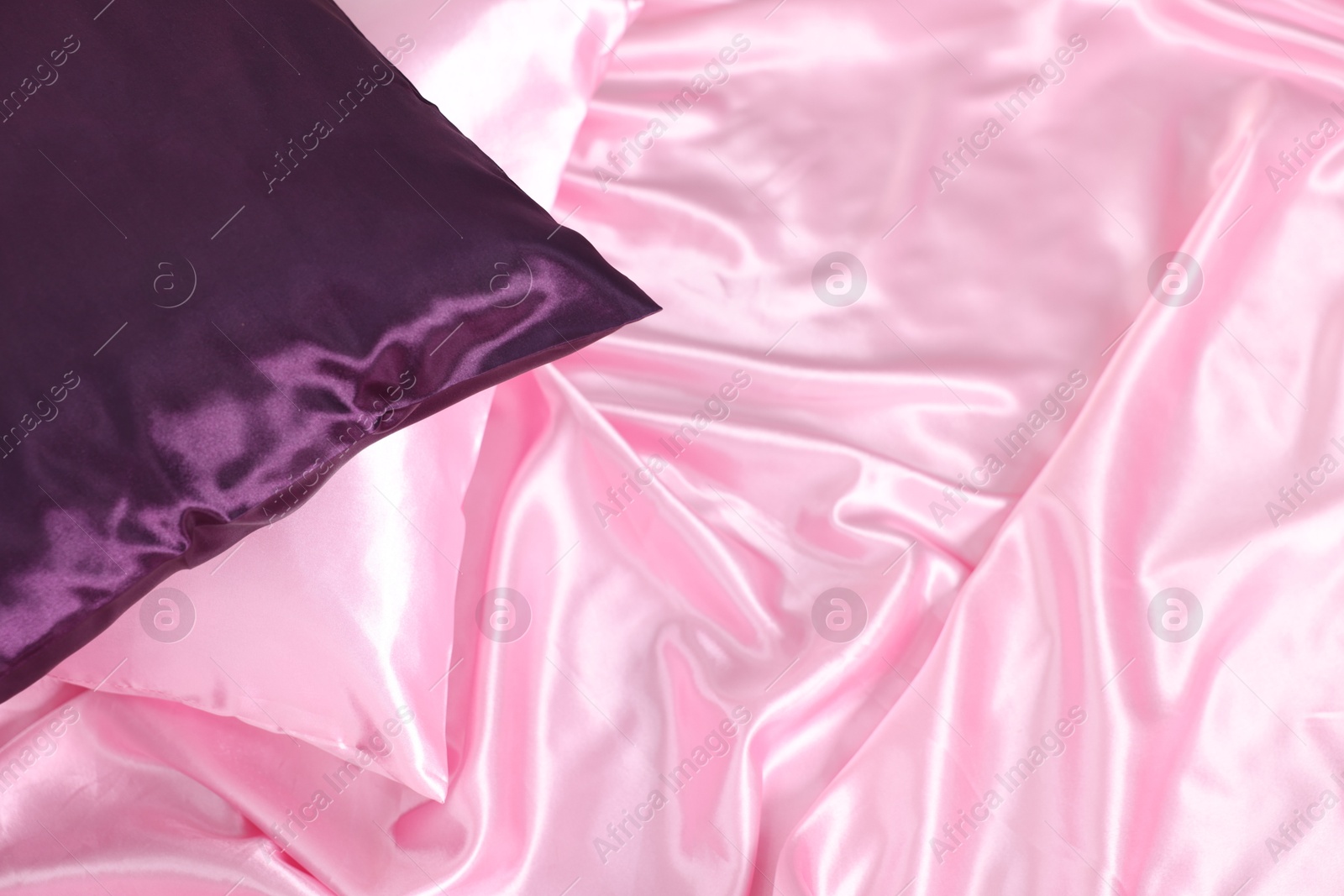 Luxury pink silk linens and pillows on bed, above view Photo of Luxury pink silk linens and pillows on bed, above view
