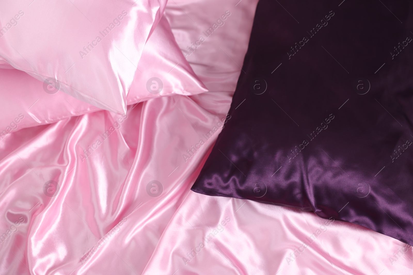 Luxury pink silk linens and pillows on bed, above view Photo of Luxury pink silk linens and pillows on bed, above view