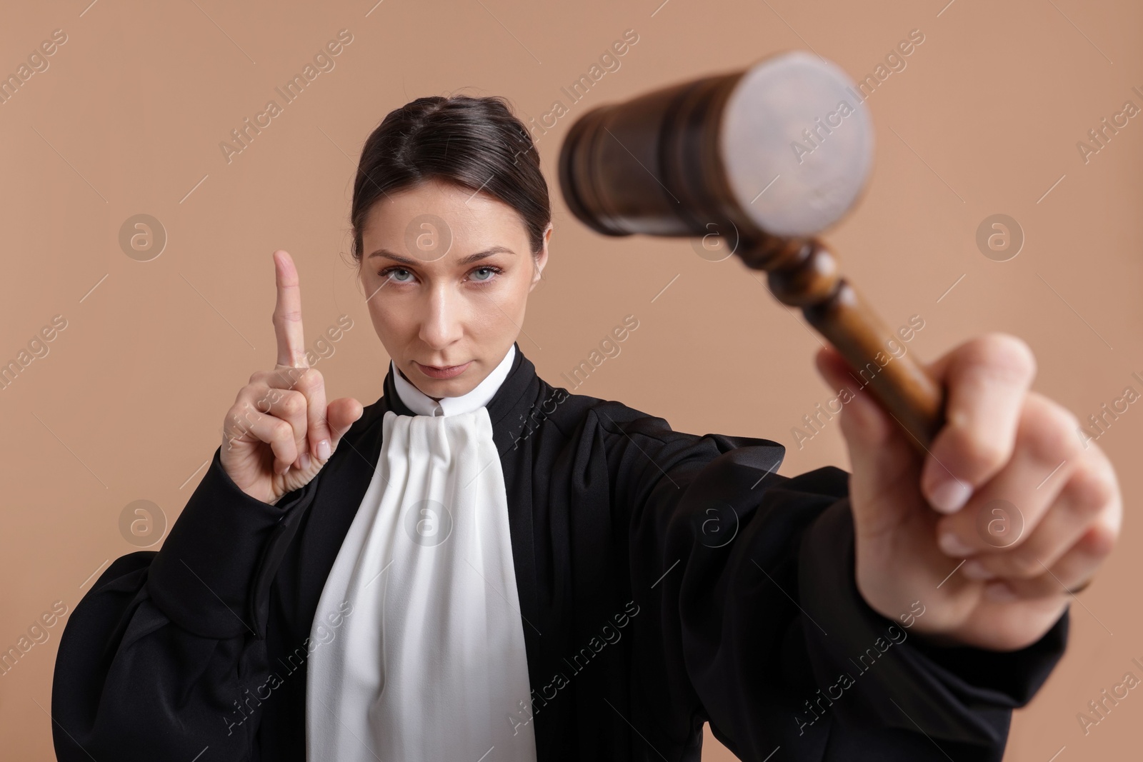 Judge with mallet on light brown background Photo of Judge with mallet on light brown background
