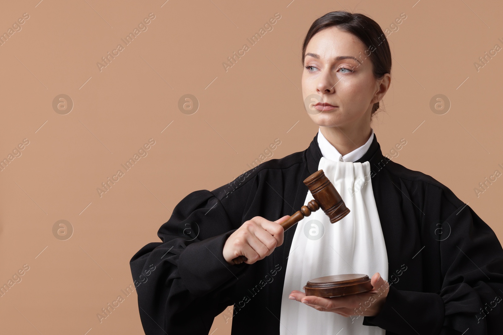 Judge with mallet and sound block on light brown background, space for text Photo of Judge with mallet and sound block on light brown background, space for text