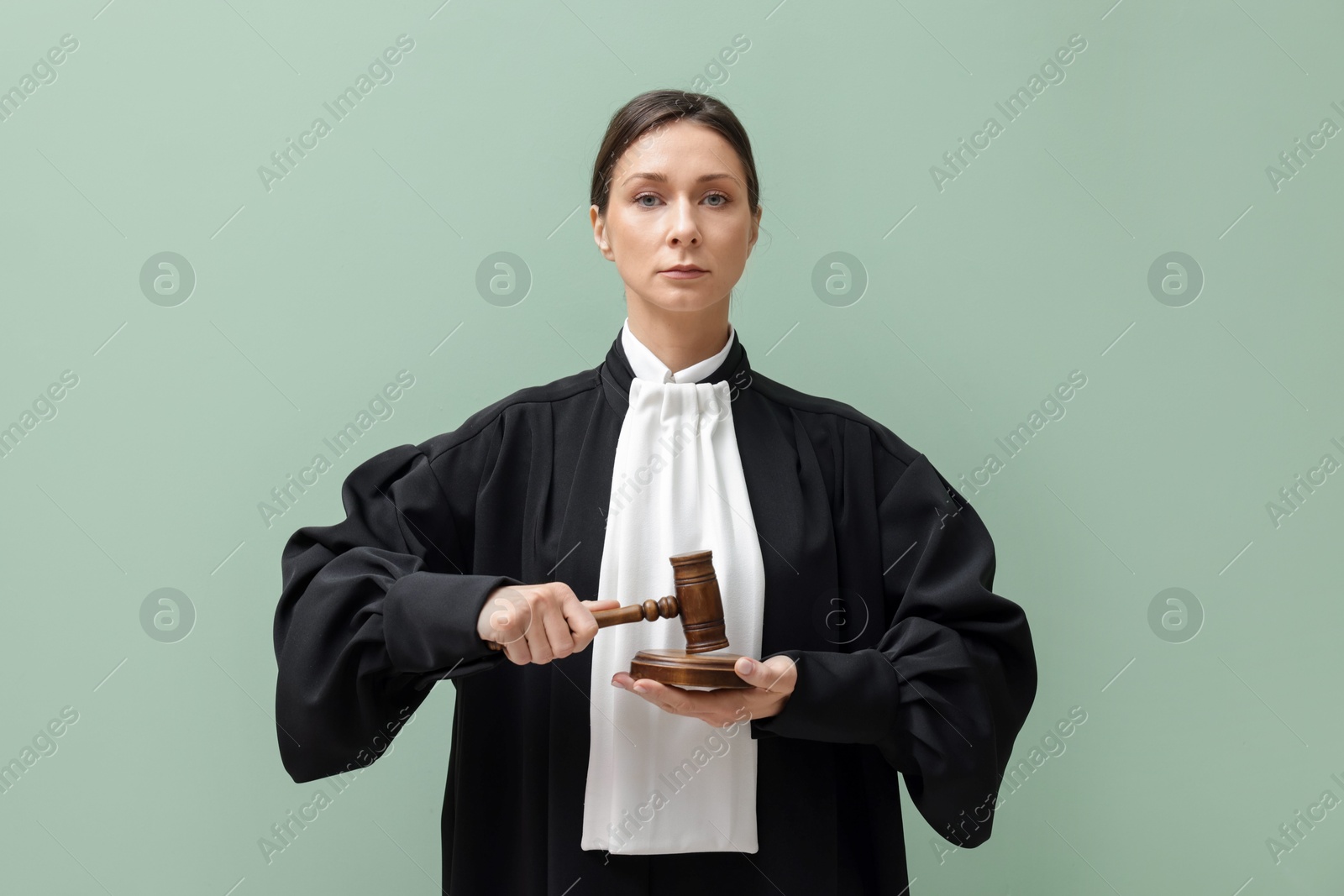 Judge with mallet and sound block on light green background Photo of Judge with mallet and sound block on light green background