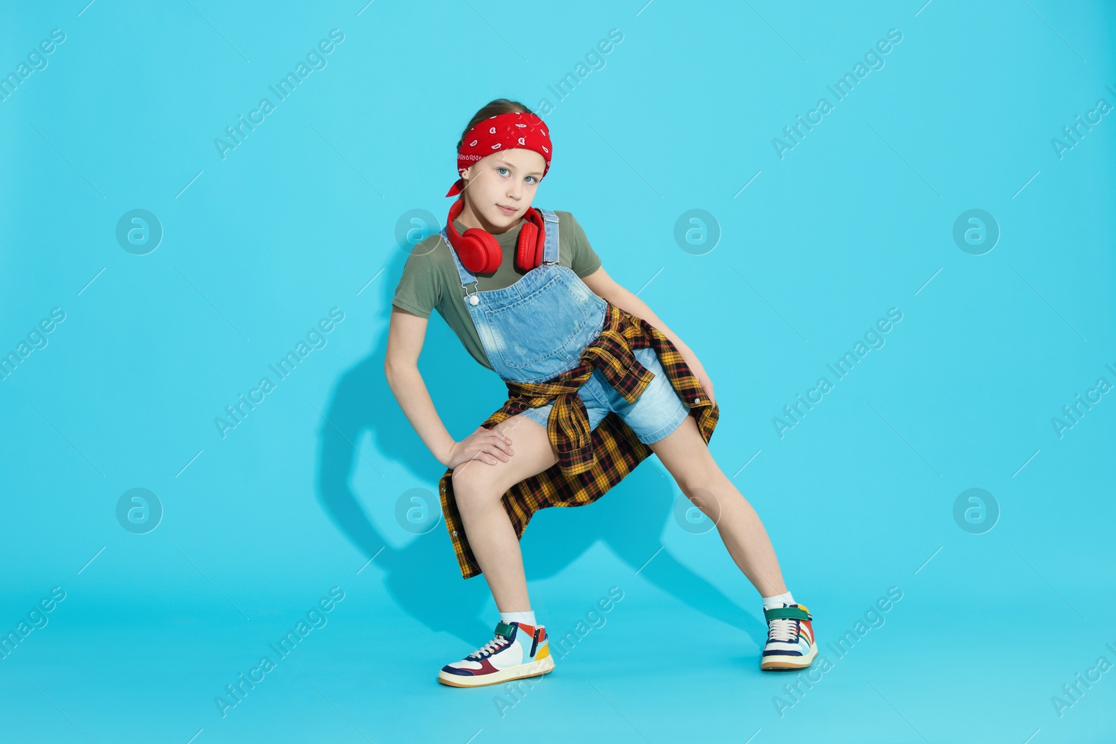 Girl with headphones dancing on light blue background Photo of Girl with headphones dancing on light blue background