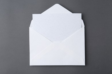 Photo of Blank greeting card in paper envelope on dark grey background, top view